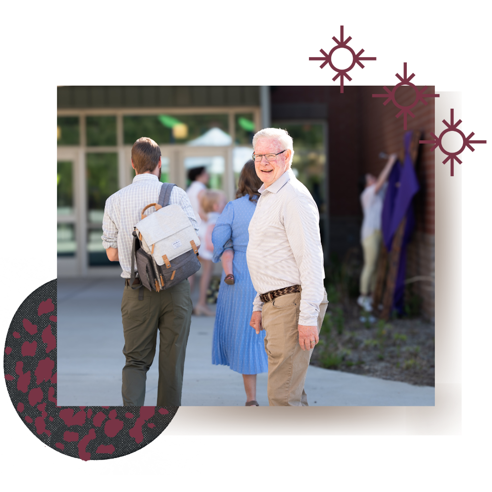 Older man smiling outside entrance to Lyons Farm Elementary after welcoming a young family to church
